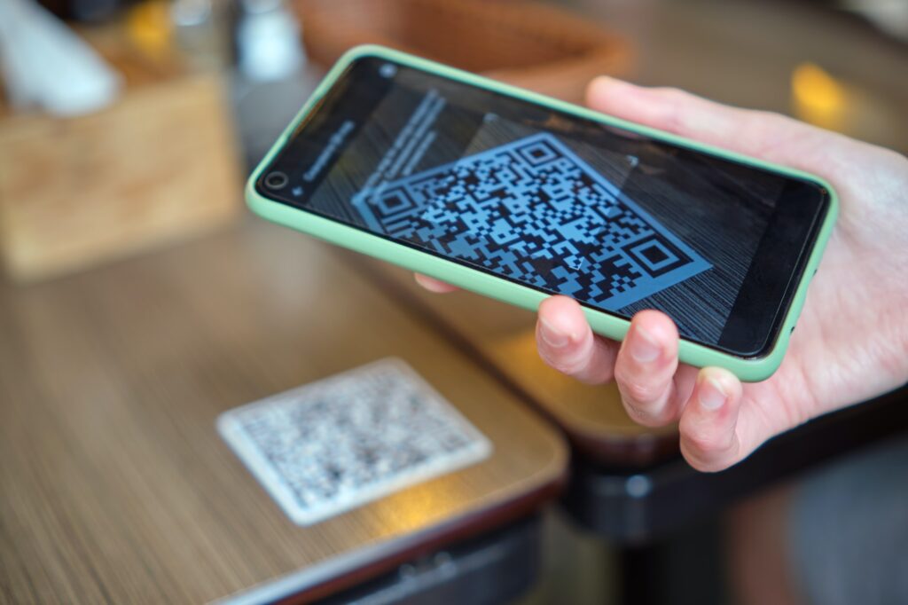 Closeup of guest hand ordering meal in restaurant while scanning qr code with mobile phone for